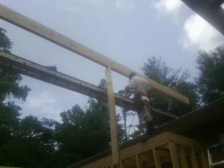 Carpenter setting a ridge beam over a new addition frame — Ice Dam Removal by Roofing Brothers in Ottsville