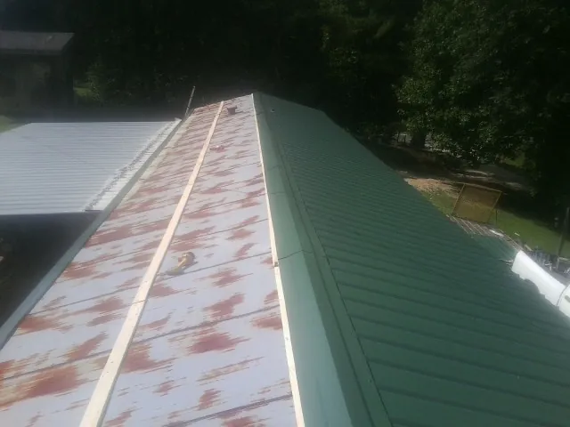 Old rusted panels beside newly installed green metal roofing — Wind Damage Roof Repair by Roofing Brothers in Ottsville