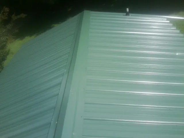 New green metal panels meeting at the ridge of a roof — Flat Roof Repair work by our crew in Ottsville