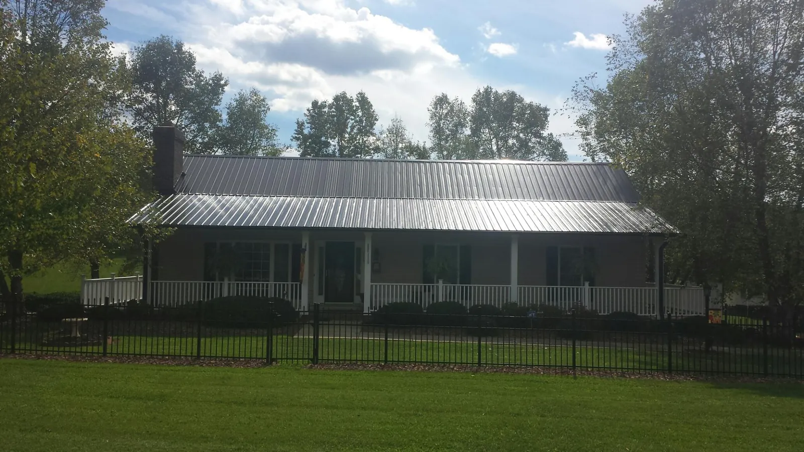 Gray metal roof on a brick ranch with a full width front porch — Gutter Guard Installation work by our crew in Ottsville