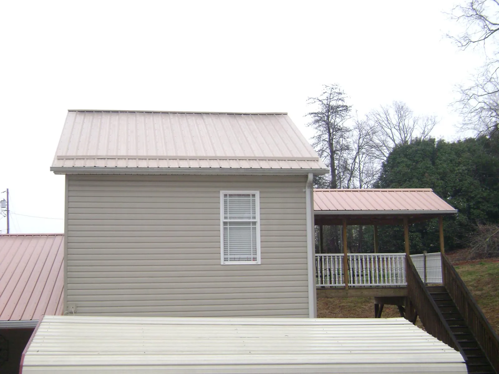 Tan metal roofs on a two story addition and attached porch, from a Roof Replacement job in Ottsville