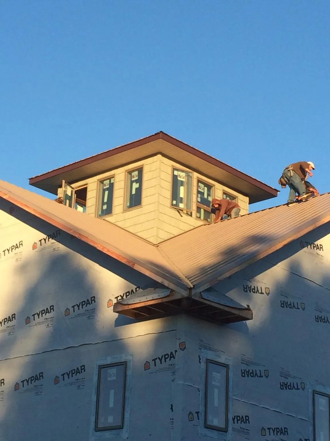 Roofers working around a rooftop cupola on a new metal roof at sunset — Roof Waterproofing in Ottsville by Roofing Brothers